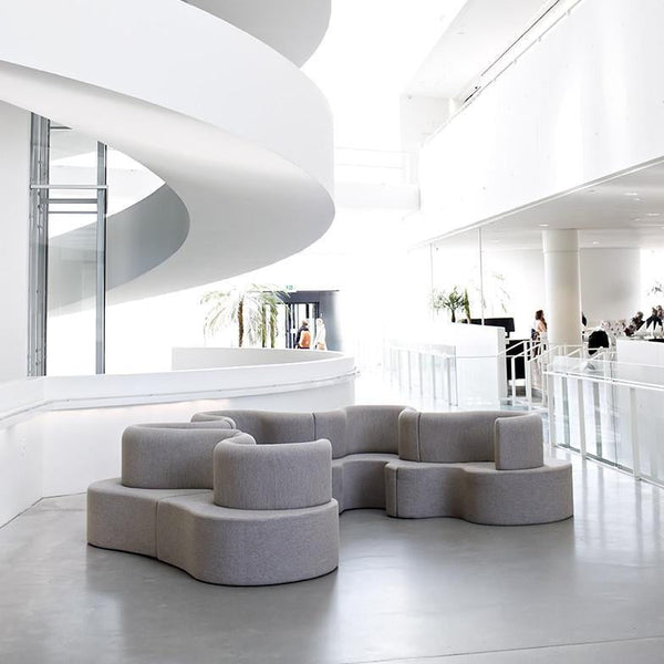 Contemporary gray modular sofa with soft curves, set against a bright, minimalist, white interior.