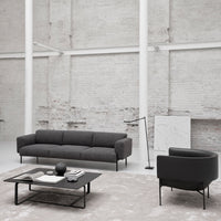 "Modern black sofa and round chair against a minimalist light-gray background with soft textures."