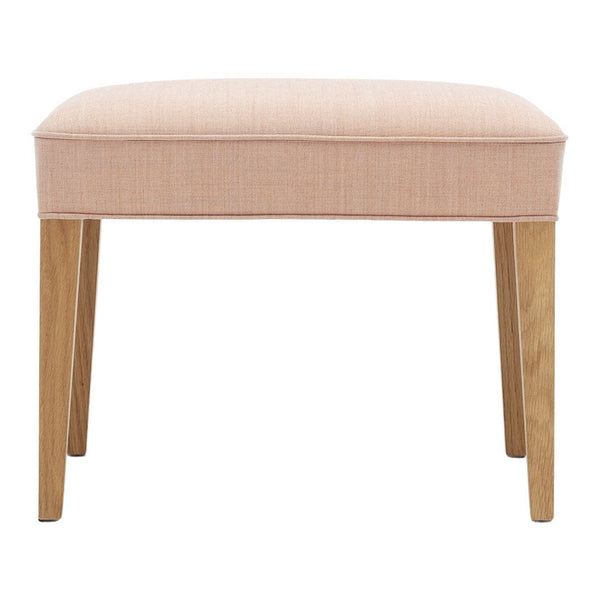 Soft pink upholstered stool with a smooth texture and natural wood legs. Elegant and modern design.