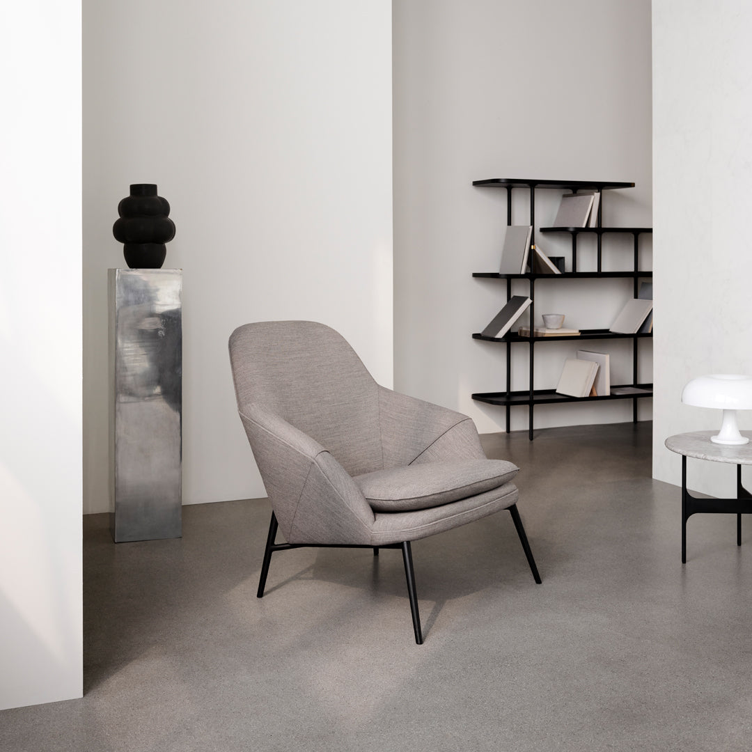Light gray upholstered chair with a minimalist design and black metal legs, set against a neutral background.