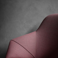 Elegant burgundy fabric chair with a smooth, modern design and subtle texture against a grey backdrop.