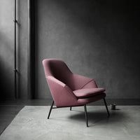 Modern burgundy armchair with sleek lines, set against a textured gray backdrop and minimalistic design.