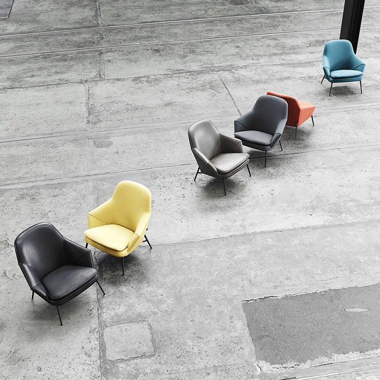 Colorful chairs in gray, yellow, black, red, and blue arranged on a neutral concrete floor, showcasing modern design.
