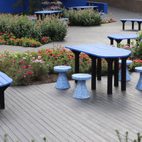 Blue patio table and stools with black legs, featuring floral pattern and vibrant garden background.