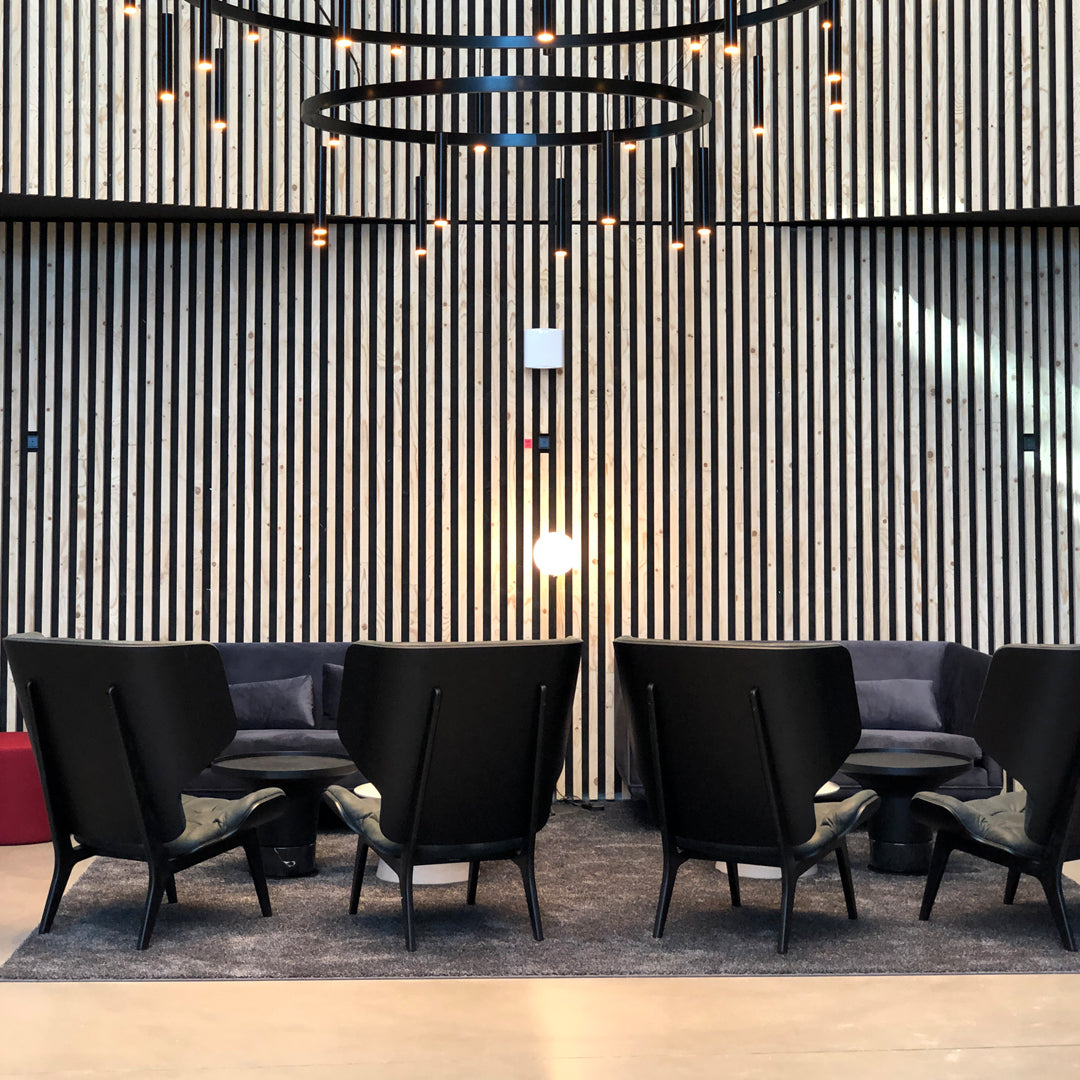 "Modern black chairs with sleek lines against a textured wood wall and soft gray rug."