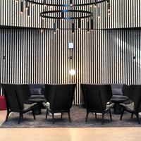 "Modern black chairs with sleek lines against a textured wood wall and soft gray rug."