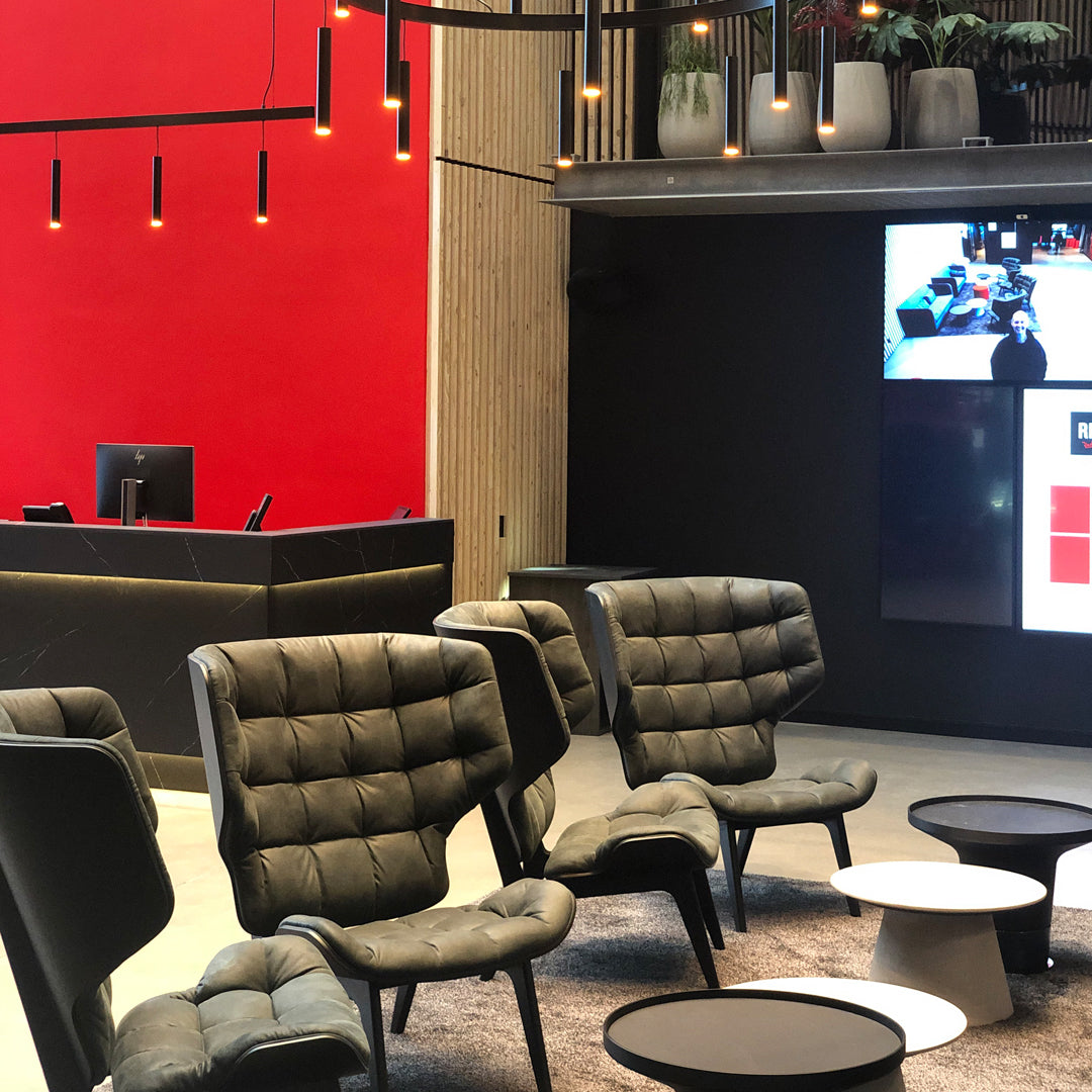"Modern black chairs with quilted fabric against a vibrant red wall and sleek black tables, creating a stylish contrast."