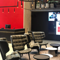"Modern black chairs with quilted fabric against a vibrant red wall and sleek black tables, creating a stylish contrast."