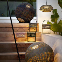 Woven wicker lanterns in black, green, and natural tones with unique circular and rectangular patterns.