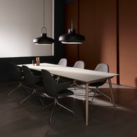 Modern dining table with a light wood top, gray chairs, and black pendant lights against a warm, dark-toned backdrop.
