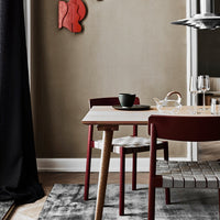 Modern dining table with earthy gray tones, burgundy chairs, and geometric rug patterns for a stylish dining setup.