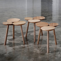 Natural wood stools with smooth circular tops and light wood tones, set against a polished concrete floor.