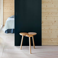 Wooden stool with natural finish, featuring round top shapes and light wood legs against a dark blue backdrop.