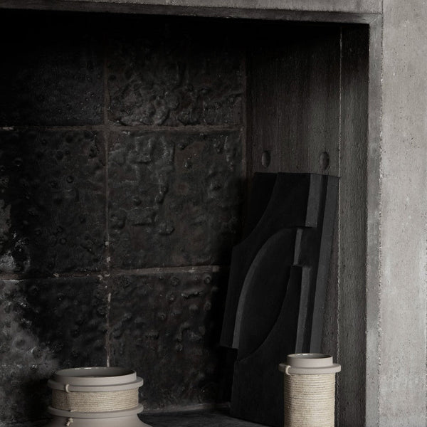 "Textured black backdrop with light-colored ceramics and a geometric black design element."