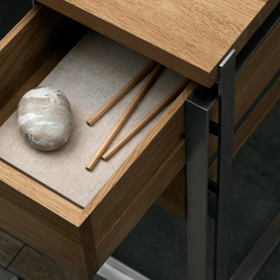 Natural wood grain drawer with beige liner, featuring a smooth stone and wooden sticks, set against a dark backdrop.