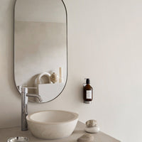 Neutral beige bathroom basin with soft curves, featuring a sleek silver faucet and minimalist decor.