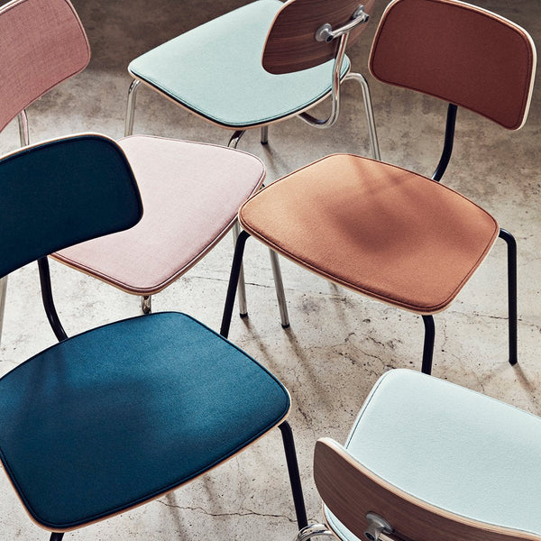 Colorful chairs featuring teal, blush, rust, and light blue upholstery with modern, minimalist designs.