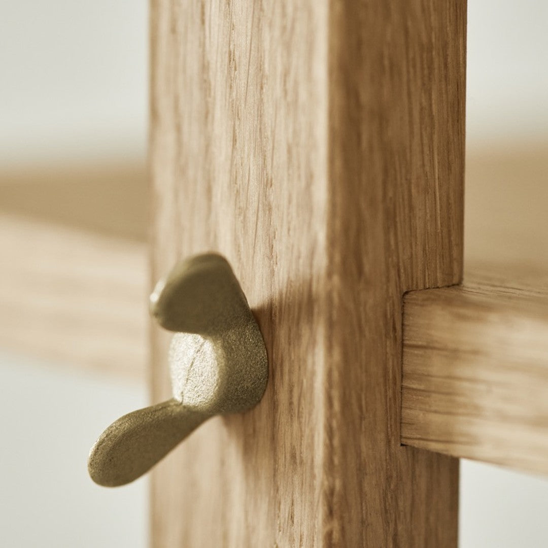 Close-up of light wood grain with a gold metal hardware accent, showcasing a modern and minimalist design.