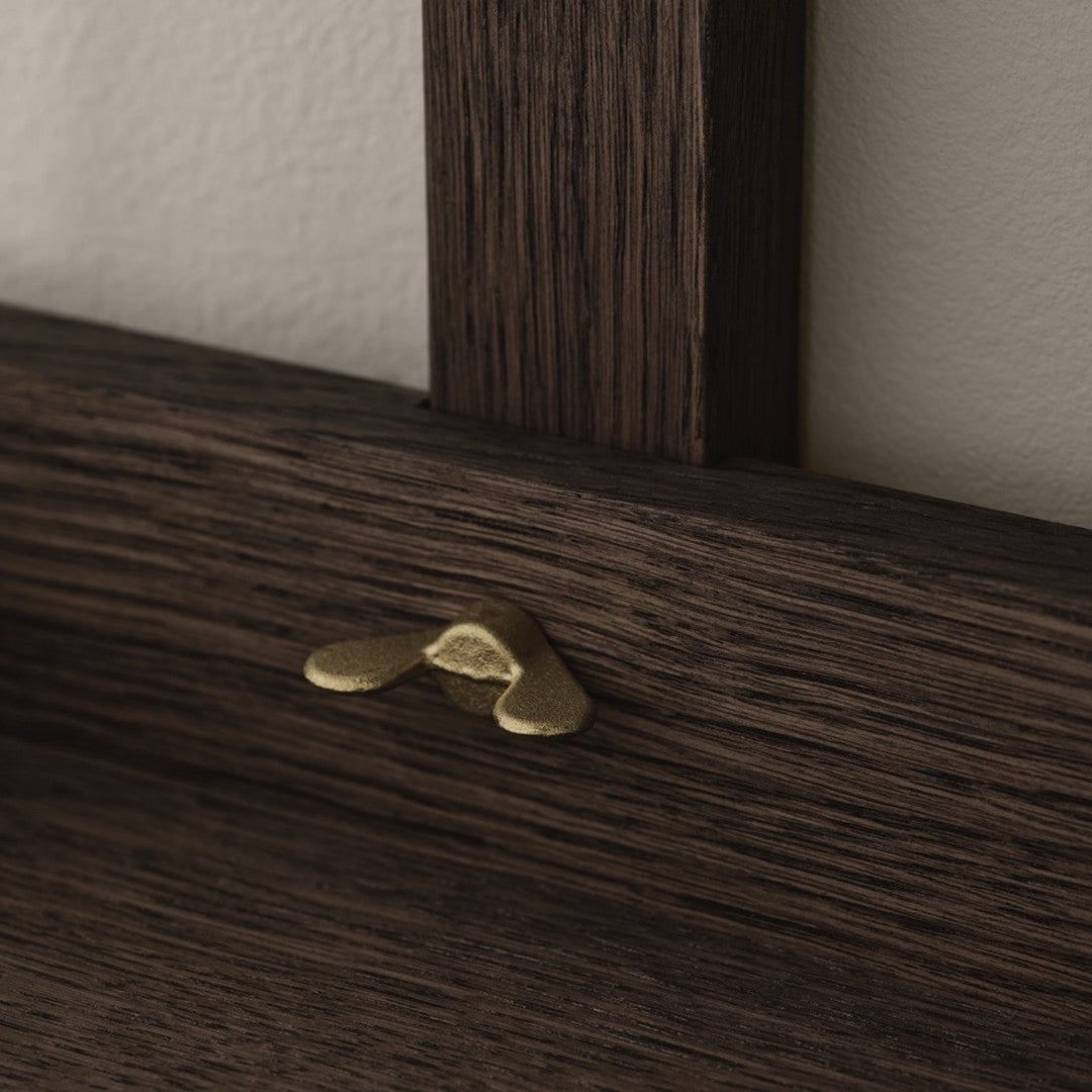 Dark wood grain with a subtle texture, accented by a shiny brass decorative piece.