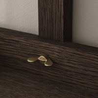 Dark wood grain with a subtle texture, accented by a shiny brass decorative piece.