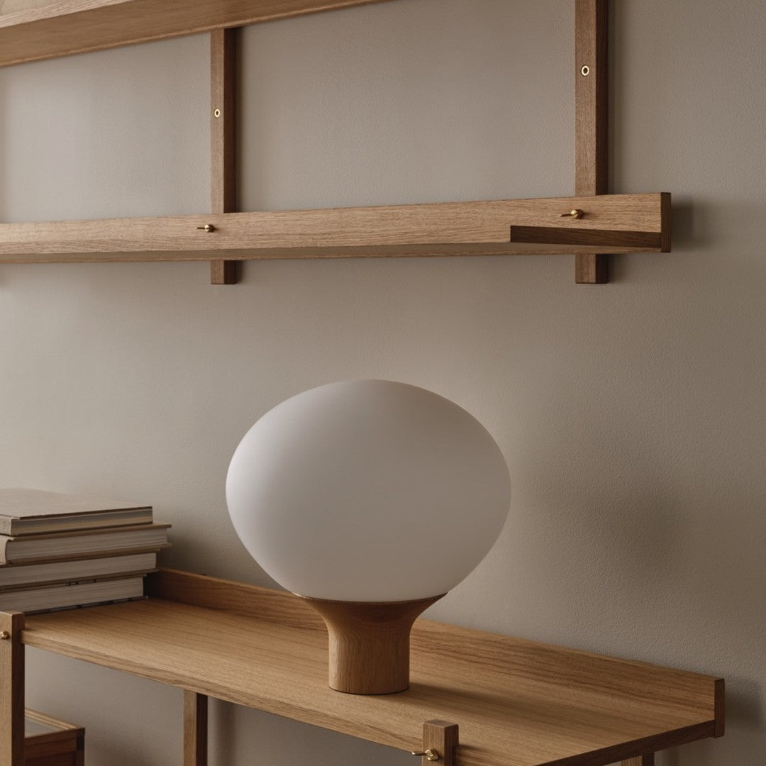 White spherical lamp on a wooden shelf, neutral tones and soft organic shapes create a modern aesthetic.