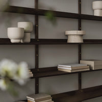Dark wooden shelves with cream and beige ceramic vases; neutral backdrop accented by stacked white books.
