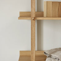Natural oak wood shelving unit with clean lines and subtle textures, featuring a light beige backdrop.