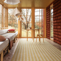 "Yellow and white checkered area rug in a cozy, sunlit room with natural wood and earthy tones."