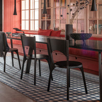 Black dining chairs on a blue and white checkered rug, with red and pink accents in a modern interior setting.