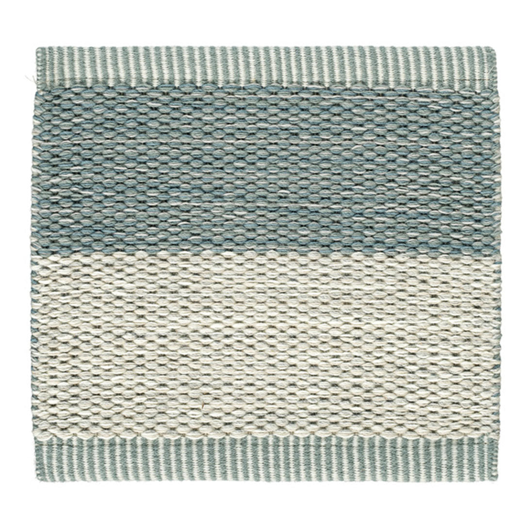 Textured area rug in soft teal and cream stripes with a woven pattern. Ideal for modern home decor.