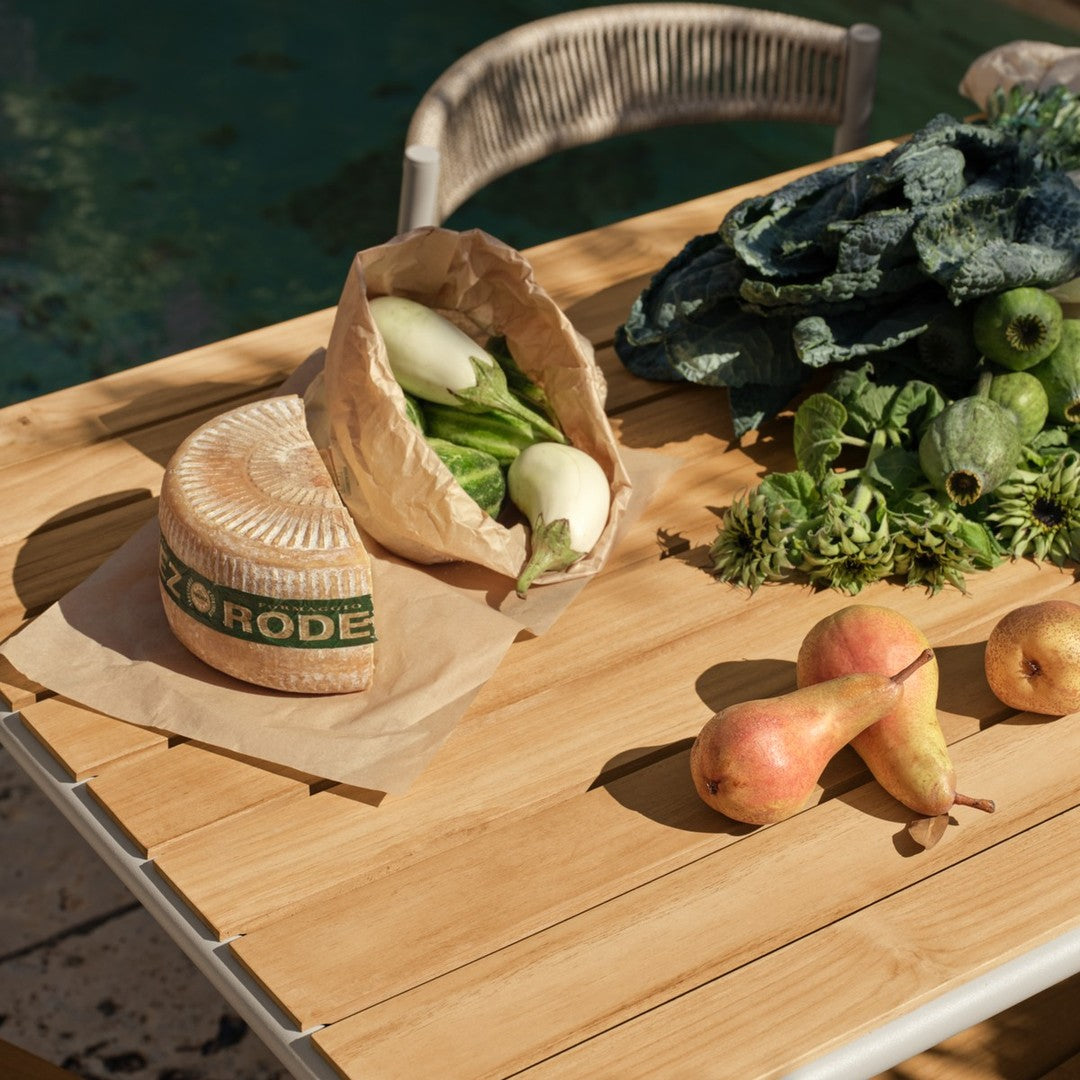 "Natural wood table with fresh greens and pears, featuring earthy tones and subtle textures in a sunlit outdoor setting."
