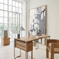 Modern wooden desk with metallic accents, featuring a minimalist black and white wall art in a bright, neutral-toned room.