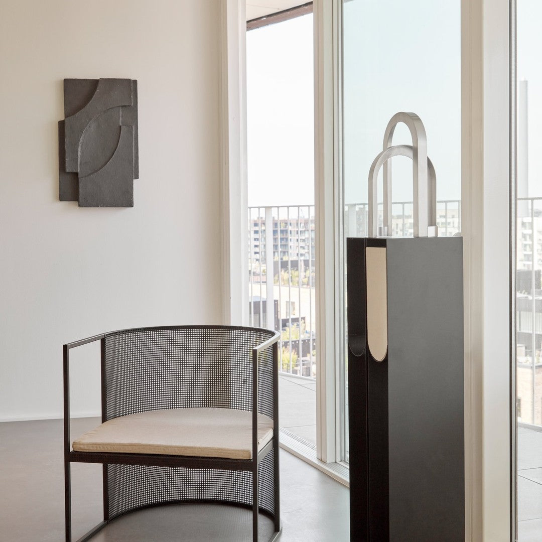 Modern black and white chair with a mesh design and light cushion, set against a bright, minimalistic interior.