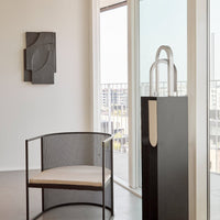 Modern black and white chair with a mesh design and light cushion, set against a bright, minimalistic interior.