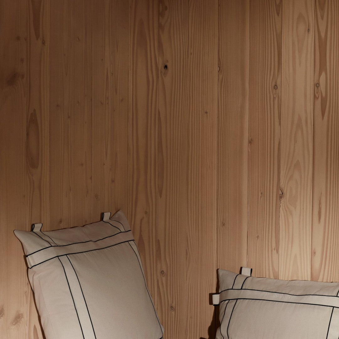 Beige pillows with navy stripes against a warm wooden wall for a cozy, stylish look. Perfect for home decor.