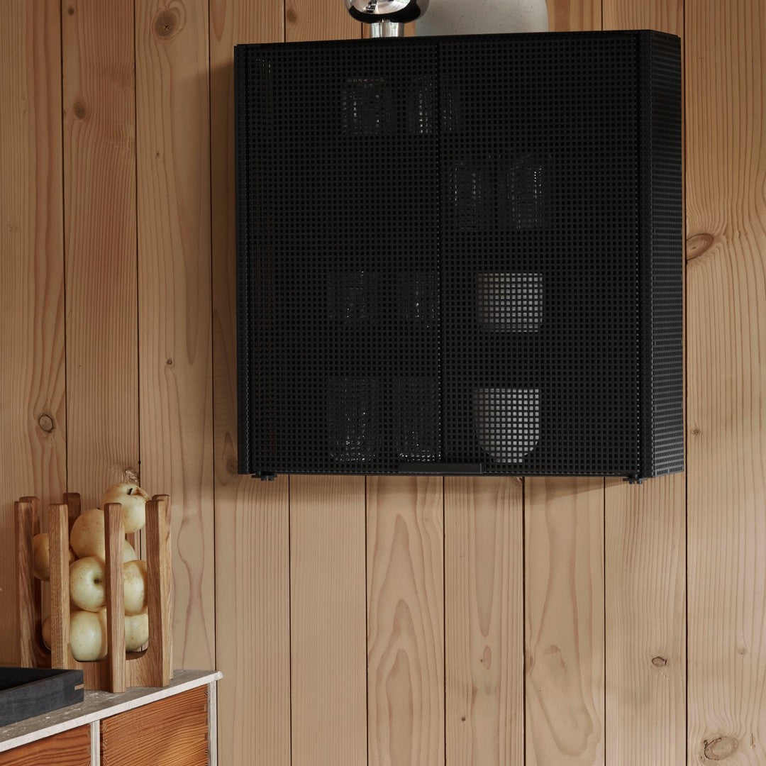 Black perforated wall cabinet with a sleek geometric pattern, mounted on wooden paneling.