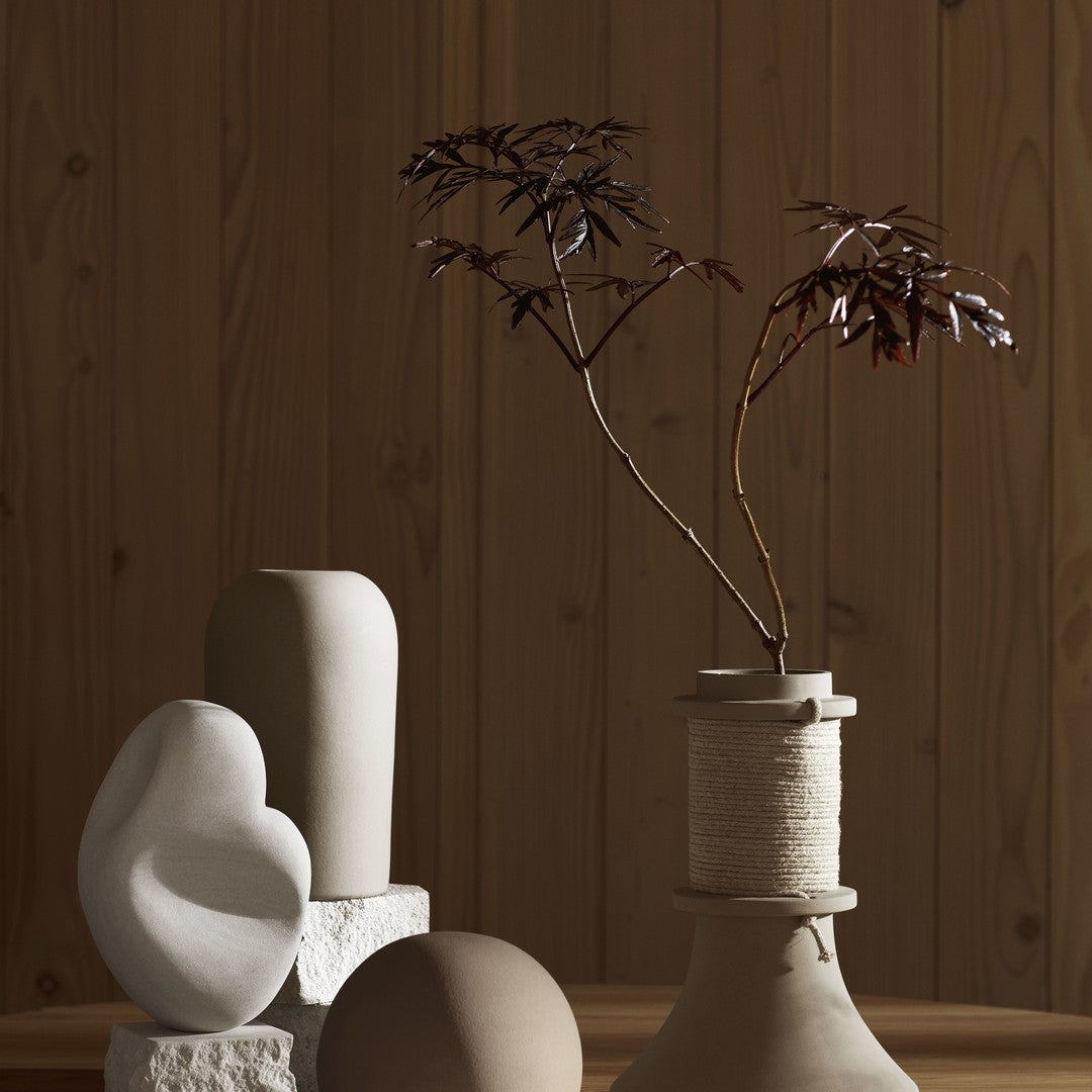 Neutral-toned vases and sculptural decor against a warm wooden backdrop, featuring soft curves and organic shapes.