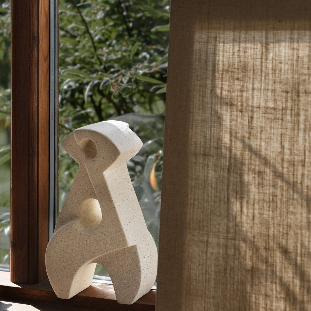 Sculptural decor in soft white against natural wood and textured beige fabric, enhancing contemporary interiors.