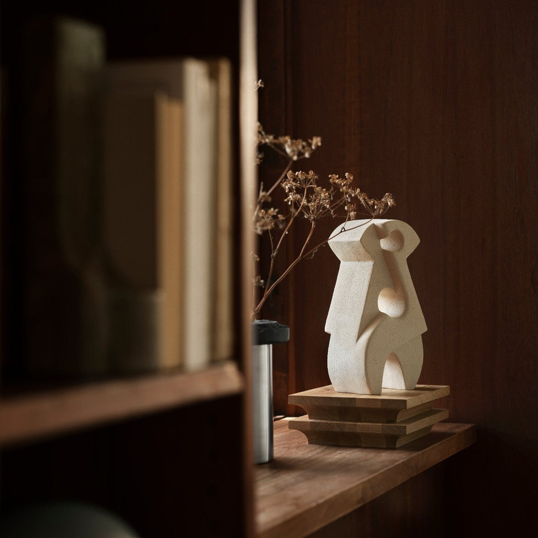 Sculptural ceramic vase in white with abstract shapes, set against a warm wood background. Sophisticated minimalist decor.