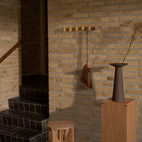 "Neutral brick wall with warm beige tones, sleek dark tile stairs, and minimalist wooden decor accents."