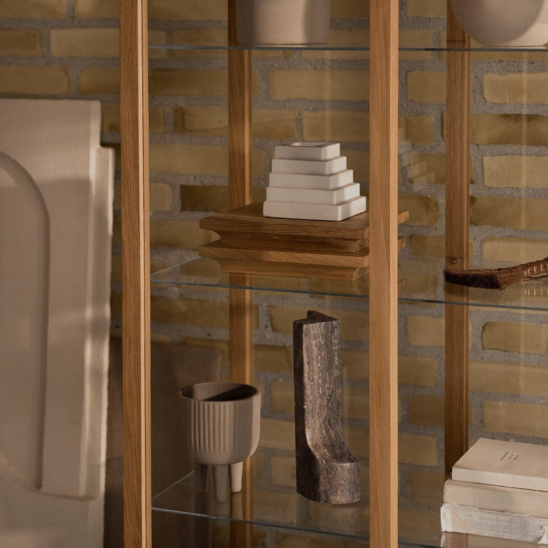 Glass and wooden display shelf featuring neutral tones with textured patterns and warm earthy hues.