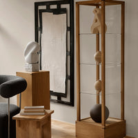 "Modern wooden display shelf featuring clear glass, neutral sculptures, and geometric patterns in a minimalist style."