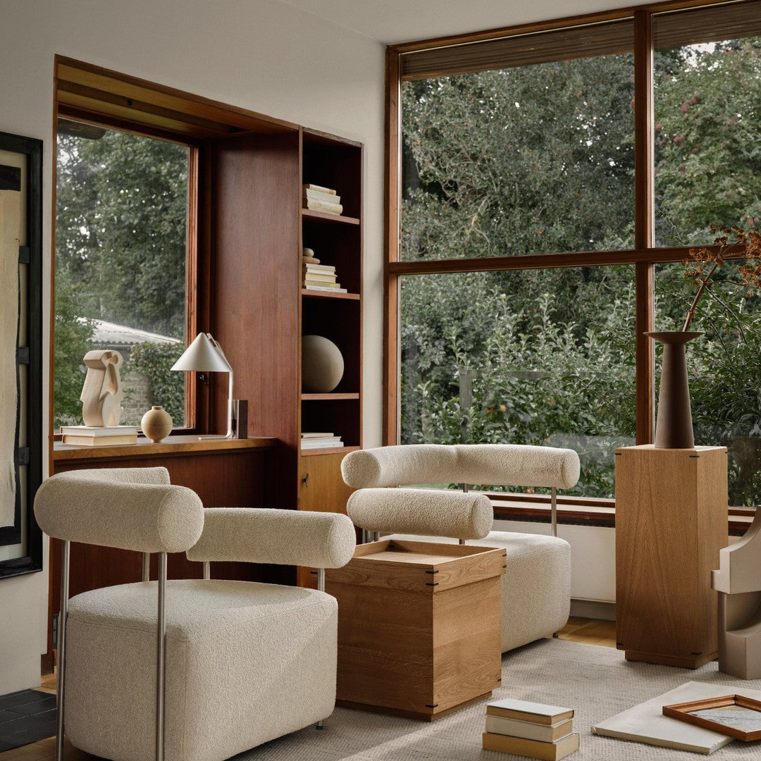 "Beige upholstered chairs with soft curves and textured wood accents in a serene, light-filled living space."