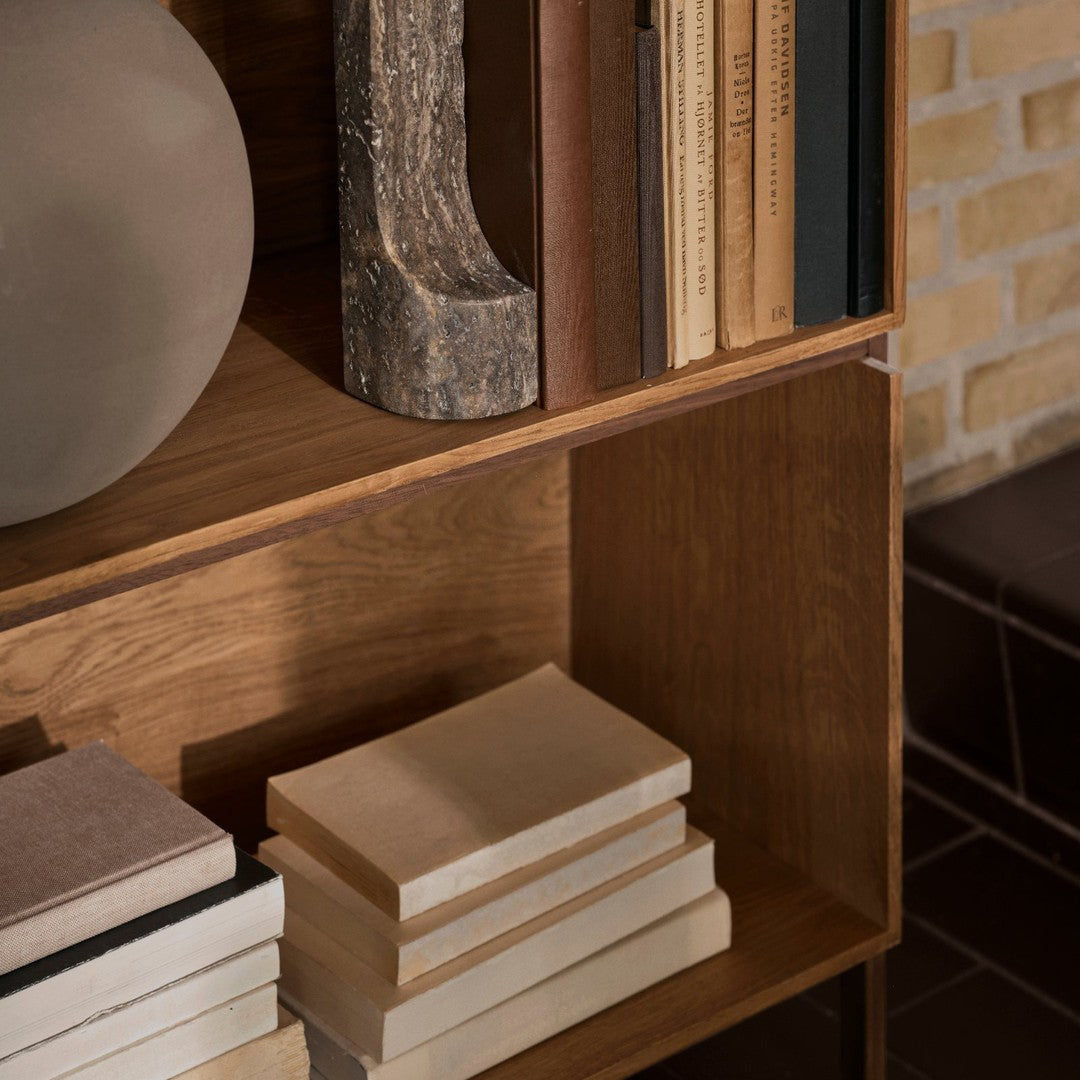 Wooden bookshelf with natural finish, neutral-toned books, and textured ceramic vase. Earthy colors and subtle patterns.