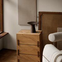 Natural wood dresser with warm oak finish, featuring simple lines and a minimalist design against a neutral background.