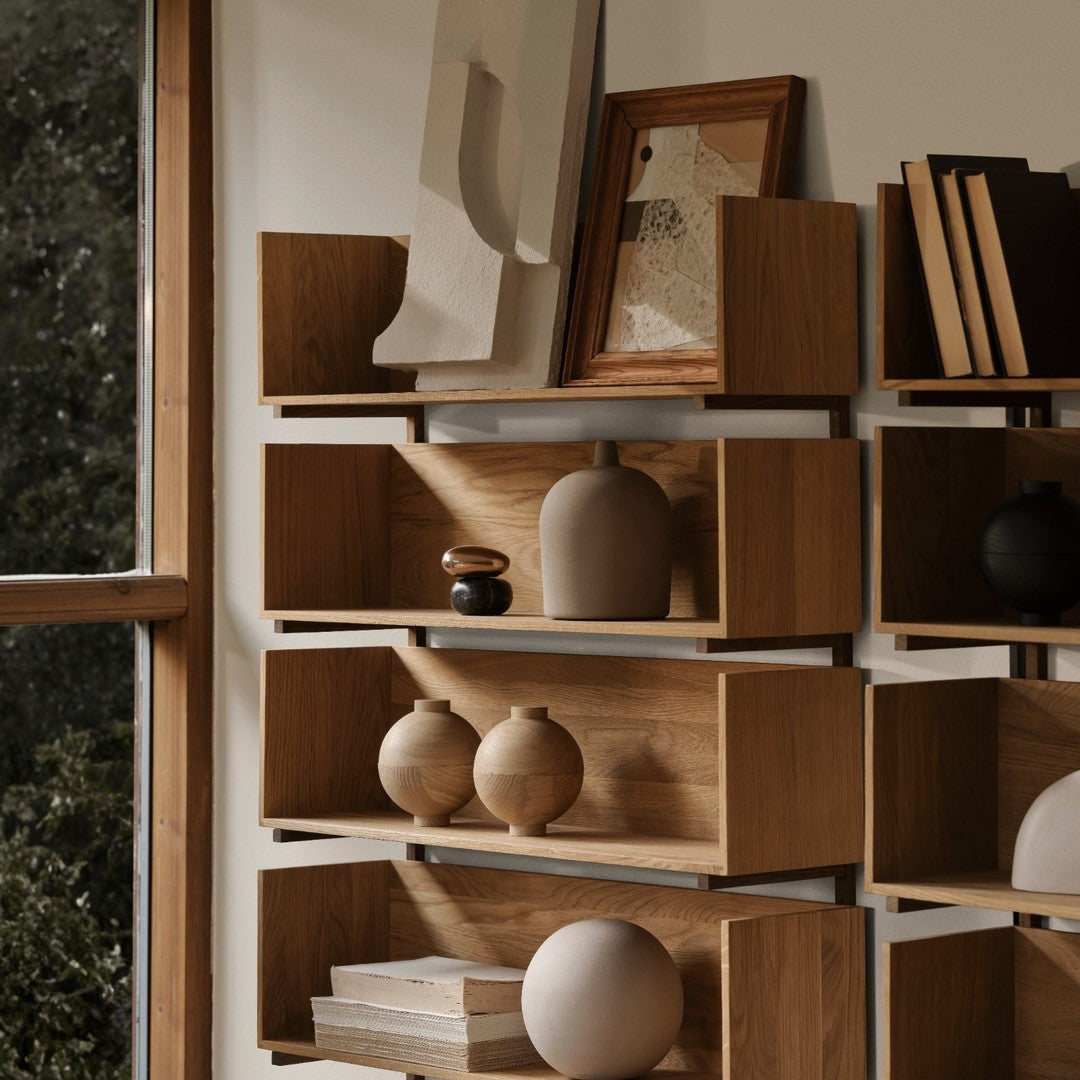 Wooden shelves in warm tones, showcasing ceramic vases in soft beige and rich browns, against a neutral backdrop.