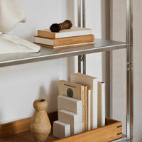 Minimalist shelf with neutral tones, light wood, and gray accents, featuring books and decorative objects.