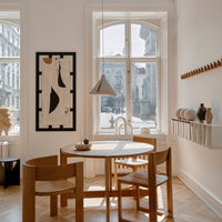 "Light wood dining set with natural tones, complemented by a black and white abstract art piece and soft beige walls."