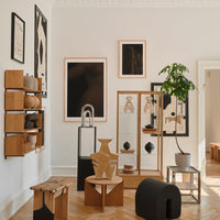 "Modern room decor featuring earthy wood tones, black and white artwork, and green plant accents."