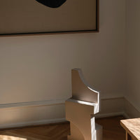 Sculptural beige decor piece with smooth curves, complementing a neutral-toned room and contrasting artwork.